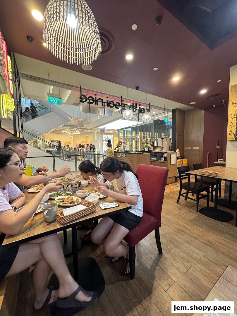 A family enjoys a meal at Soi Thai Soi Nice JEM, with mall shoppers visible in the background.