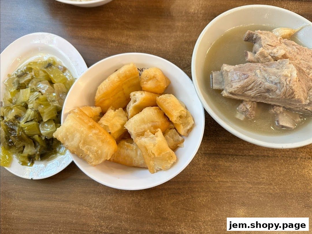 A bowl of pork rib soup with preserved vegetables and fried dough sticks.