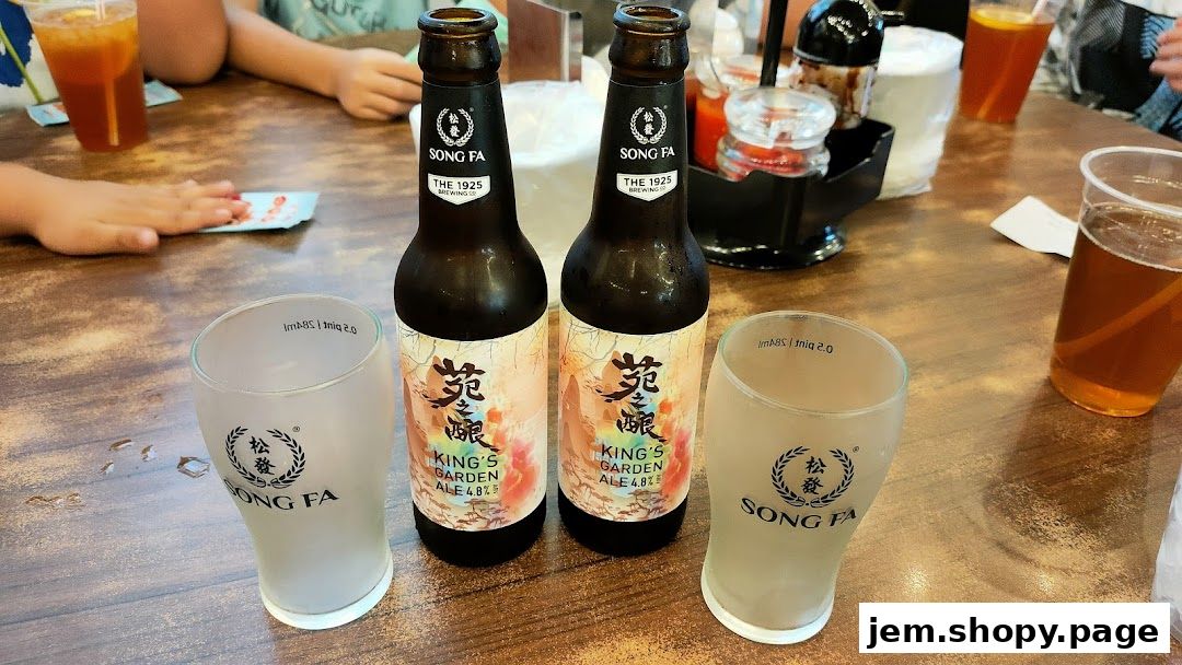 Two bottles of Song Fa King's Garden Ale with branded glasses on a wooden table.