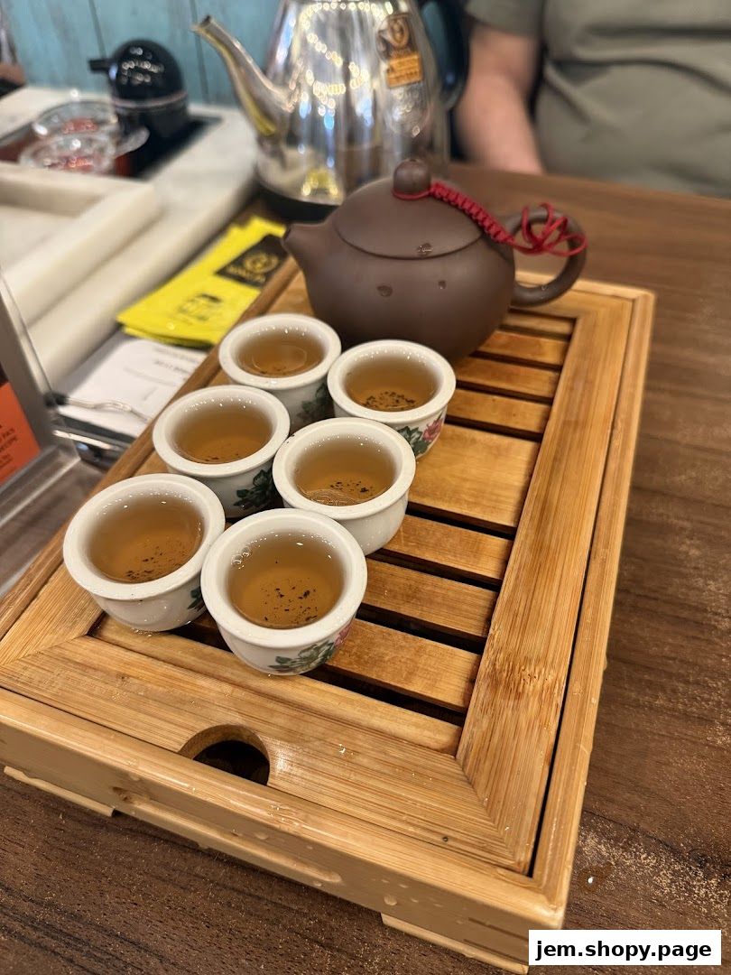 A traditional tea set with a teapot and six small cups filled with tea.