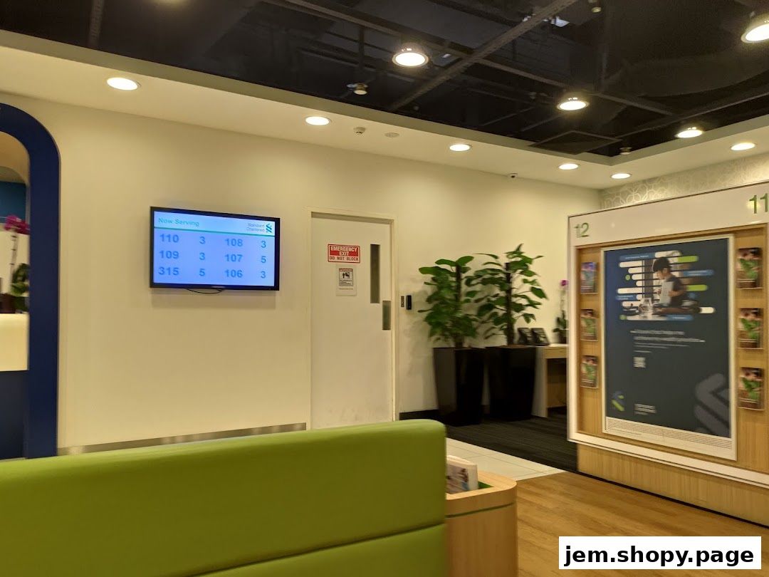 Interior of a Standard Chartered Bank branch with a digital display showing queue numbers.