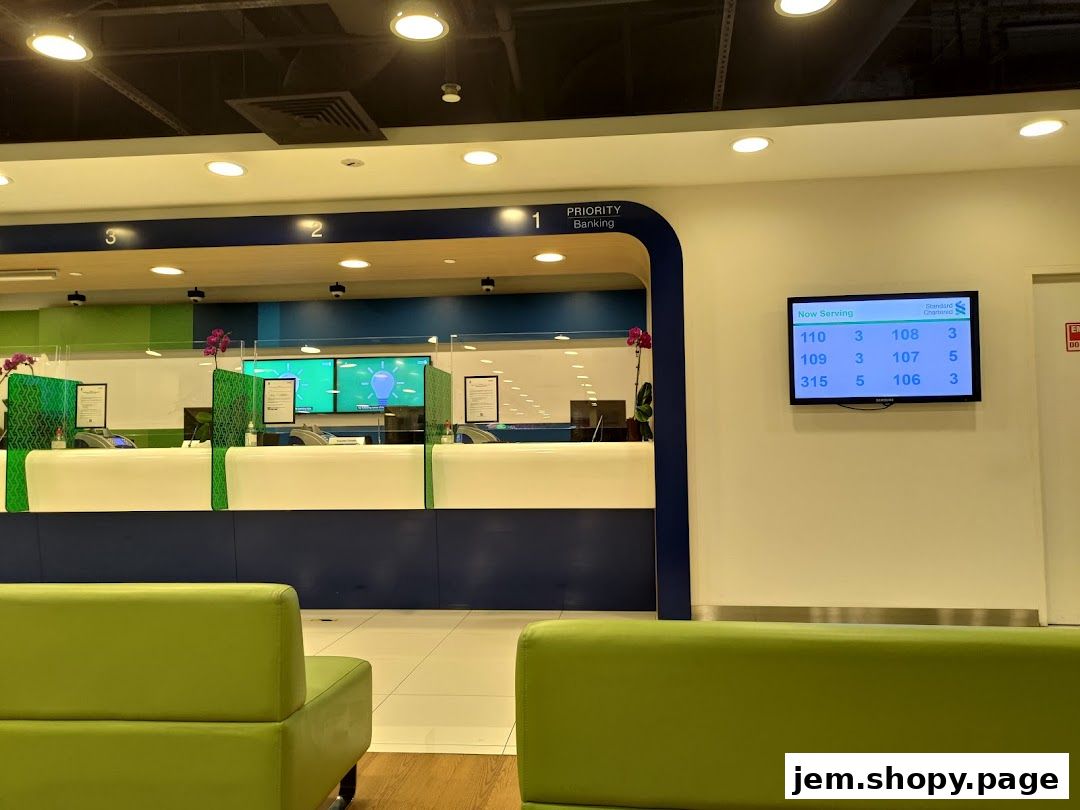 Interior of a Standard Chartered Bank branch with a queue display and priority banking section.