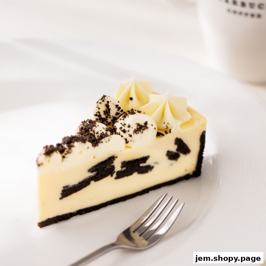 A slice of Oreo cheesecake with whipped cream and cookie crumbles on a plate.