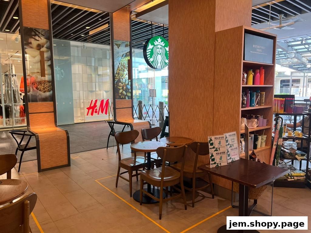 Interior view of a Starbucks with seating, merchandise shelves, and an adjacent H&M store.