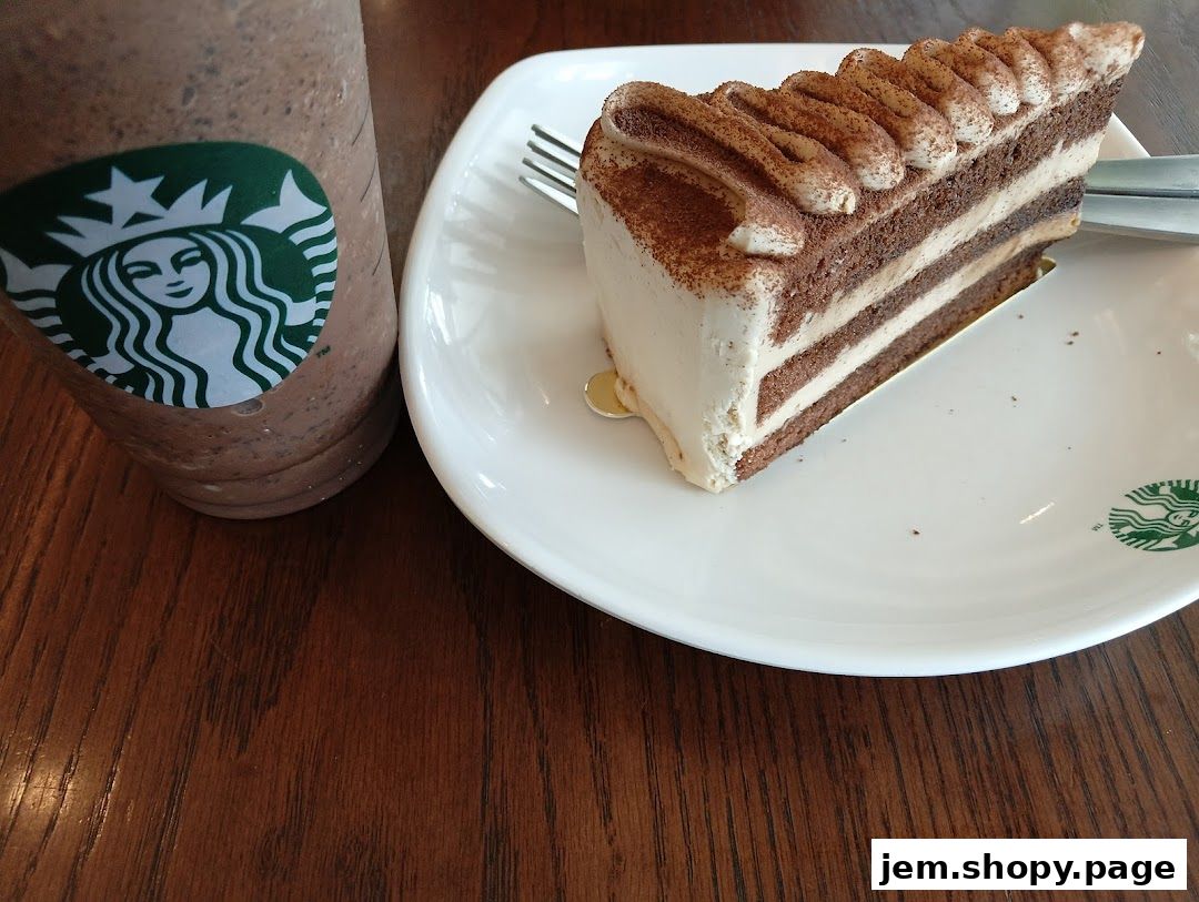 A slice of tiramisu cake and a Starbucks Frappuccino on a wooden table.