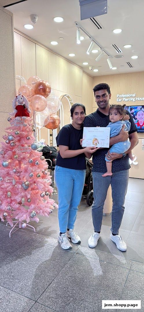 A family poses with a certificate in front of a pink Christmas tree and balloons.