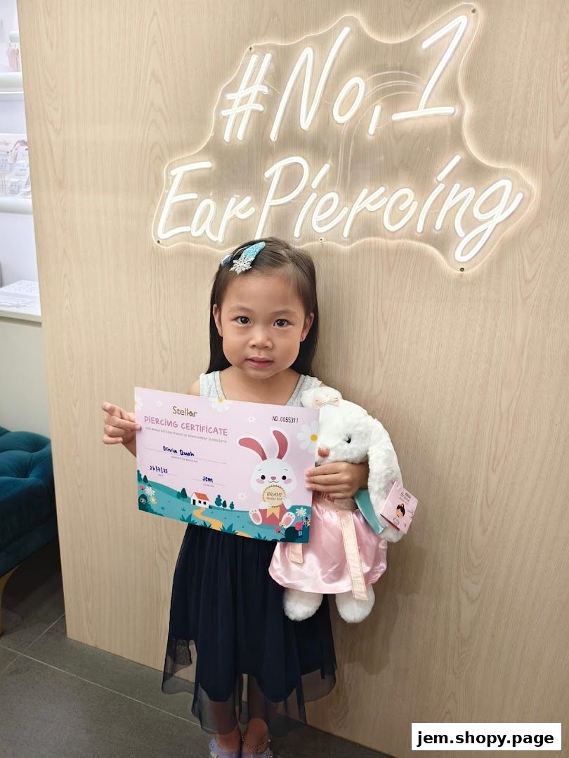 A young girl holds a piercing certificate and a stuffed bunny in front of a neon sign.