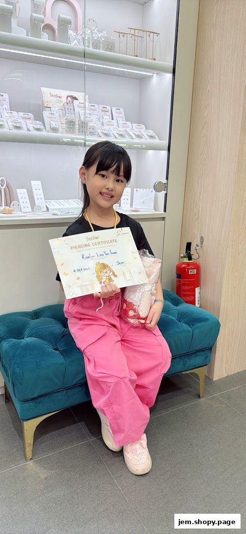 A young girl proudly holds a piercing certificate and gift bag in a jewelry store.