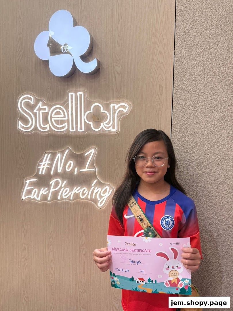 A young girl holds a piercing certificate in front of a Stellar Ear Piercing sign.