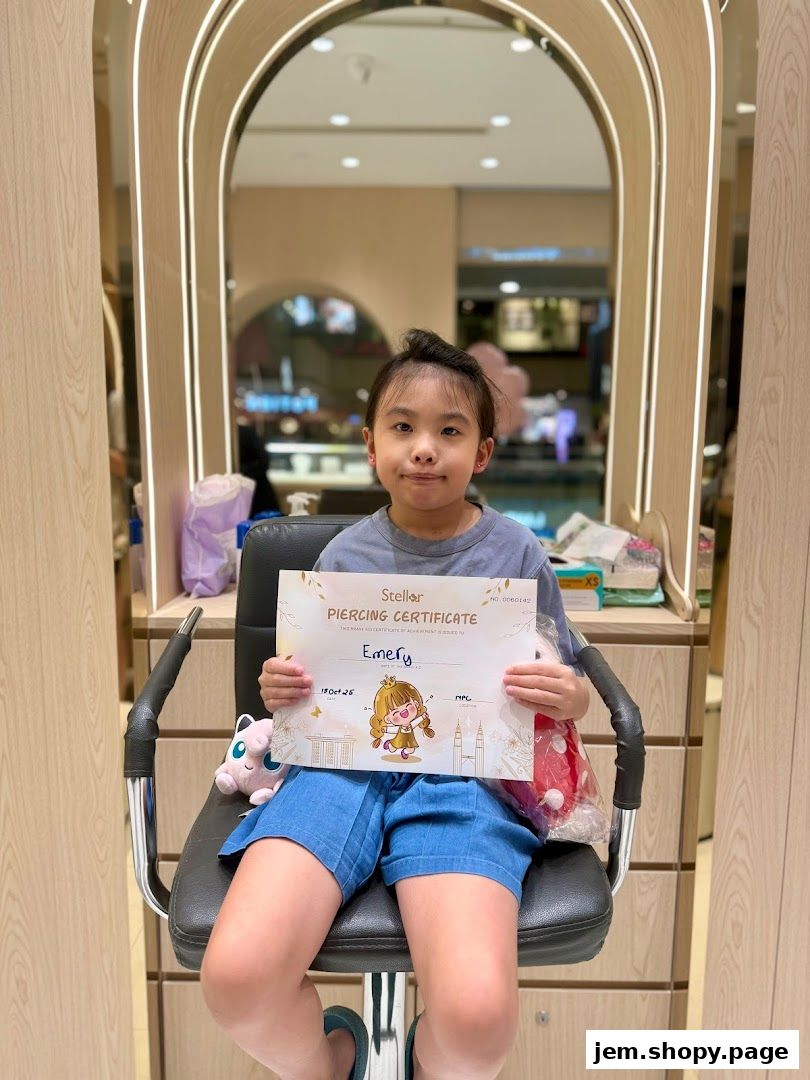 A young girl proudly holds a piercing certificate in a brightly lit jewelry shop.