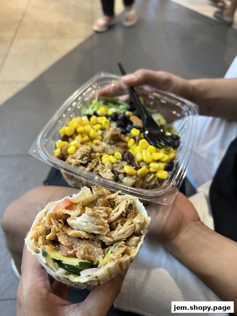 A person holds a chicken wrap and a salad with corn and beans from Stuffd.