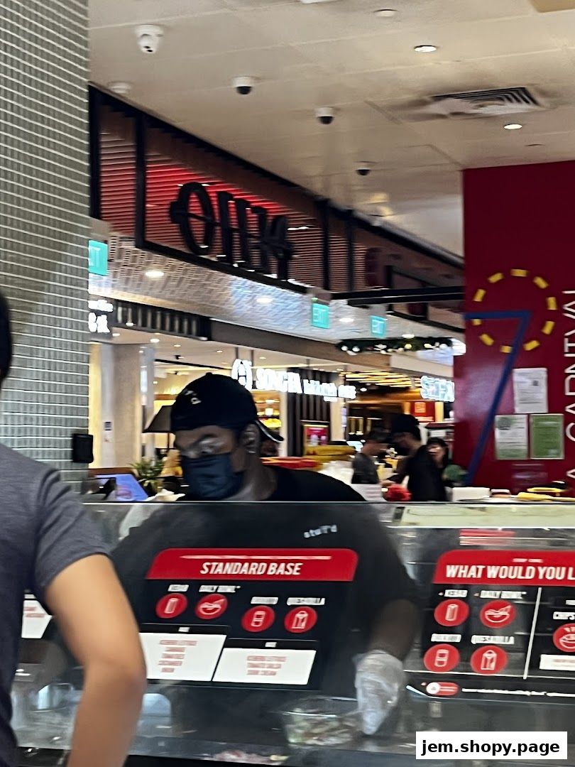 A staff member wearing a mask and gloves serves food at a counter in a restaurant.