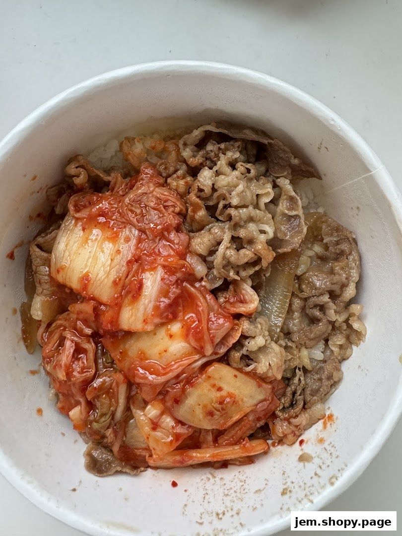 A close-up of a Sukiya Gyudon bowl with beef, rice, and kimchi.