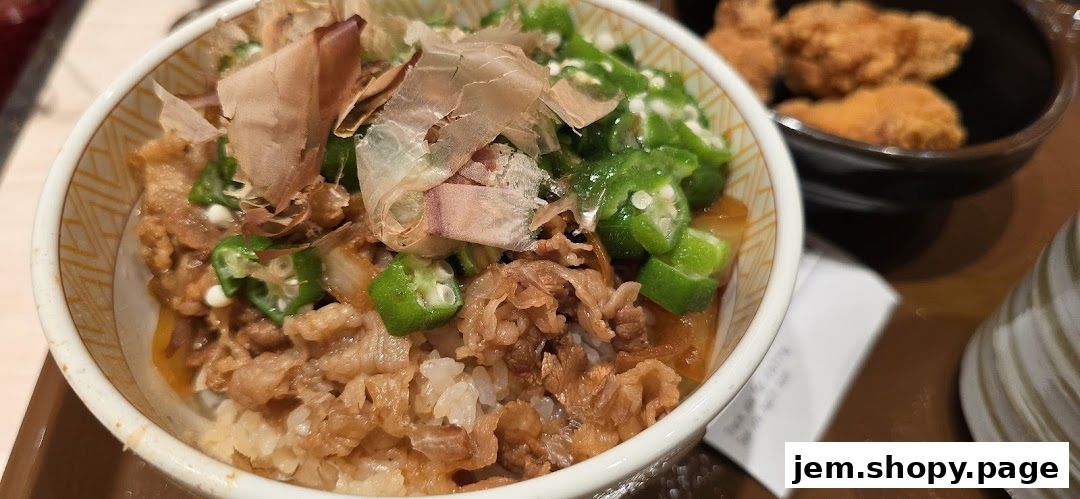 A close-up of a Sukiya Gyudon bowl with beef, rice, and okra, topped with bonito flakes.