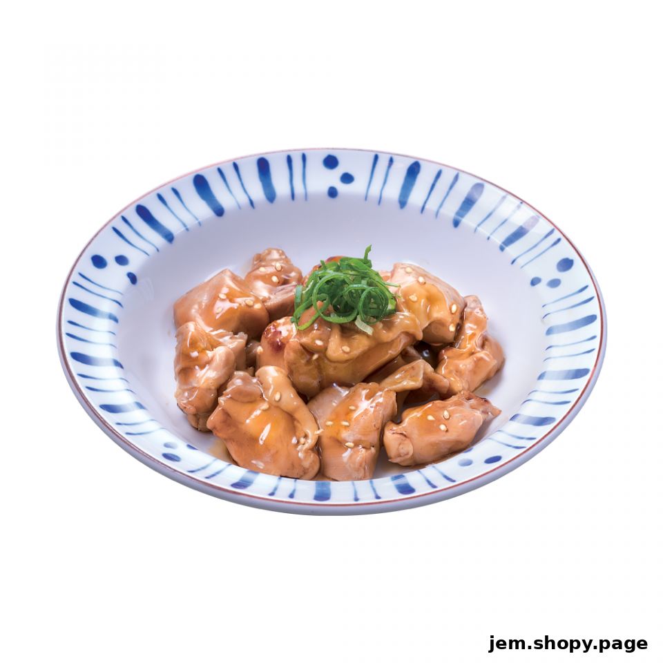 A bowl of glazed chicken pieces topped with sesame seeds and green onions.