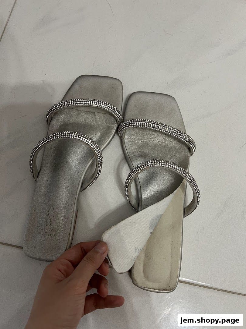 A pair of silver sandals with rhinestone straps, showcasing the 'Sunday Staples' logo.