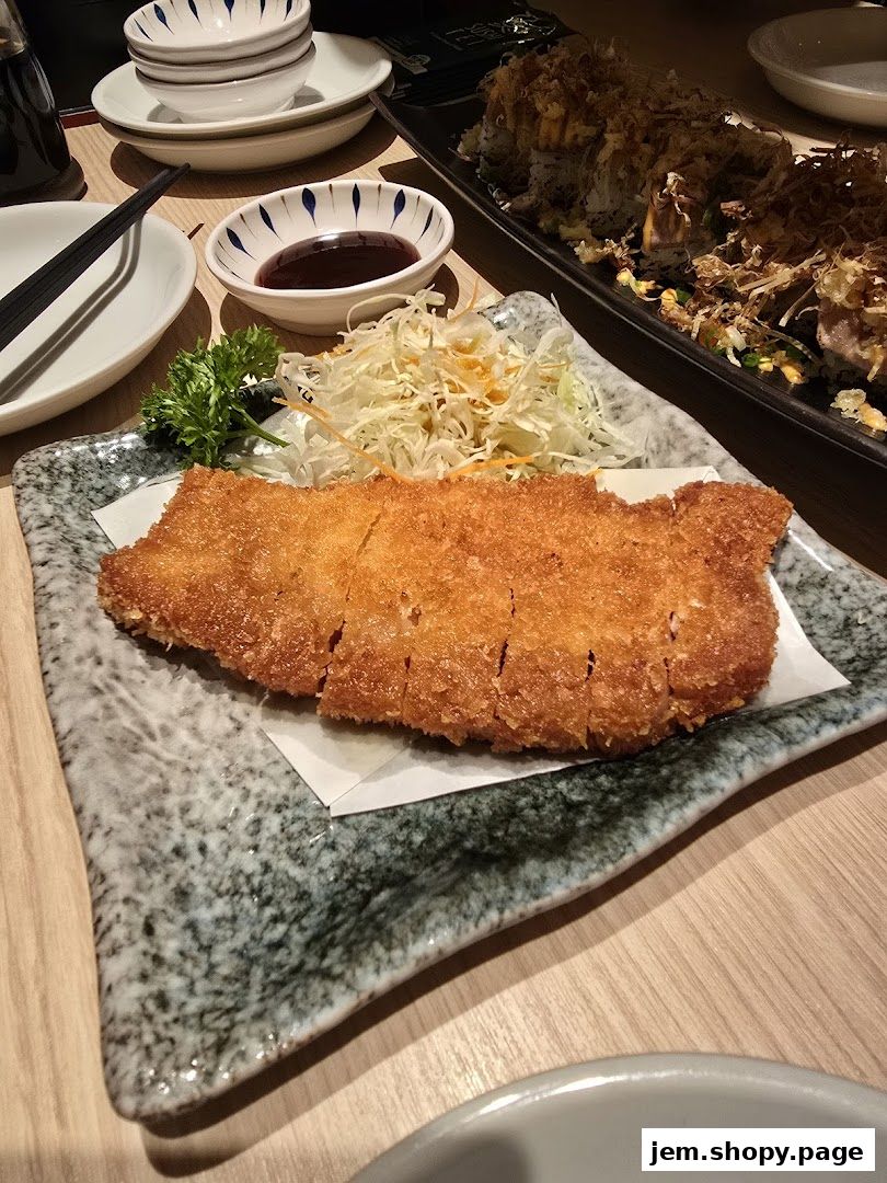 A close-up of a crispy fried cutlet served with shredded cabbage and dipping sauce.