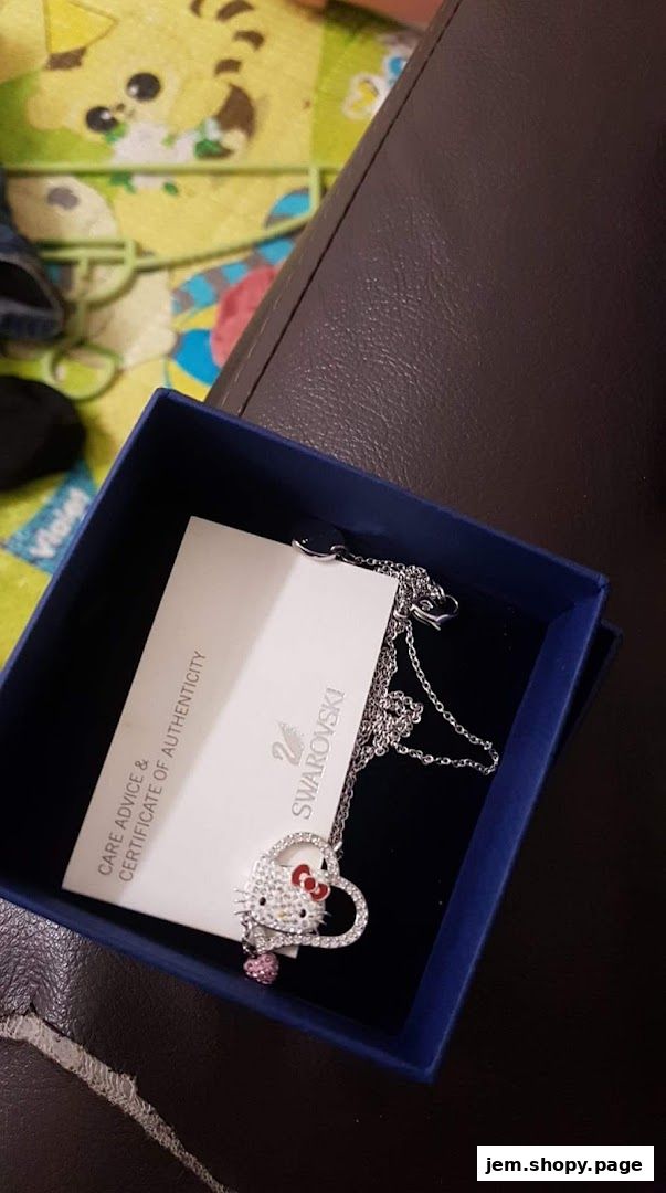 A Swarovski Hello Kitty necklace in its blue gift box with care instructions.