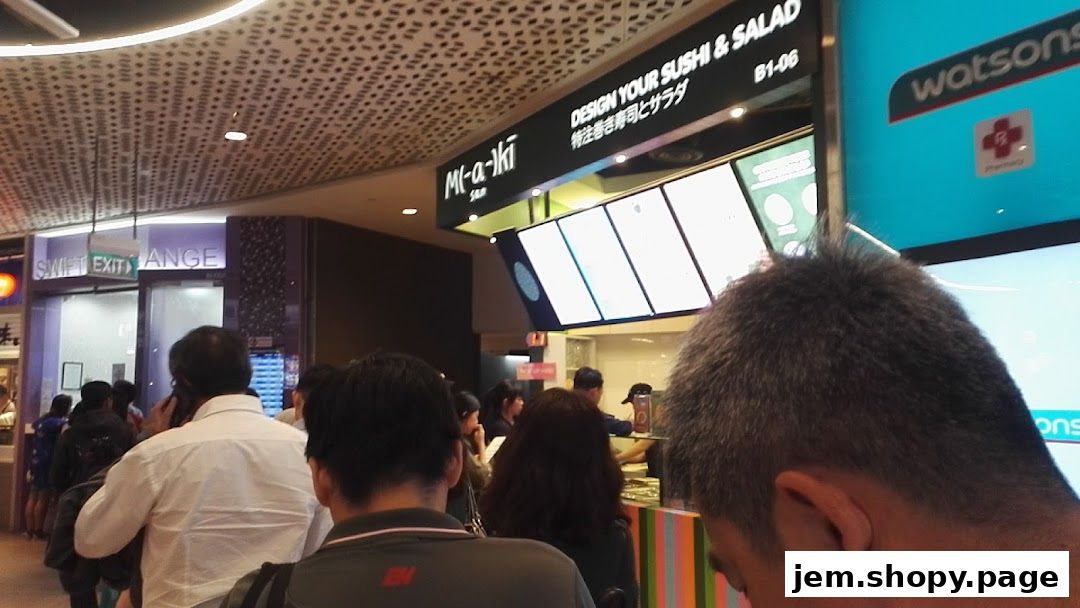 People queuing at a sushi and salad shop with a Watsons pharmacy nearby.