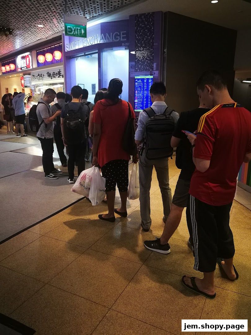 People queuing outside Swift Exchange, a currency exchange service with a digital display.
