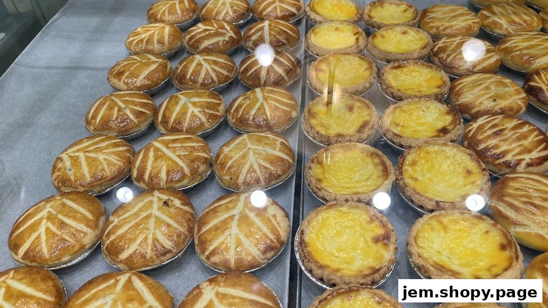 A display of freshly baked egg tarts and savory pies in a bakery.