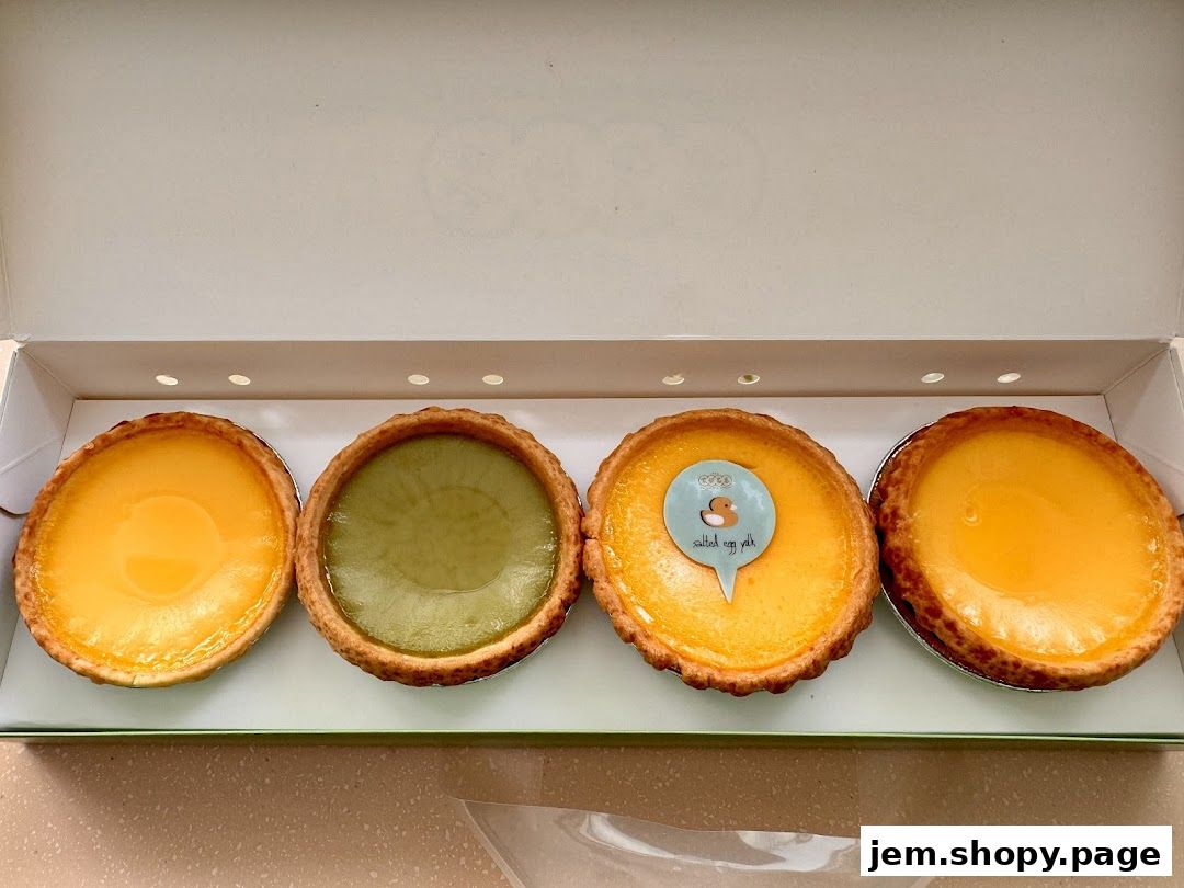 A box of four tarts, including two classic egg tarts and two with green filling.