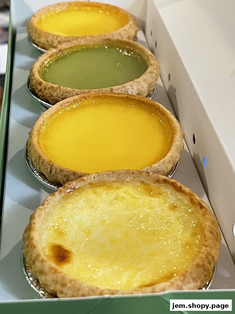 A close-up shot of four delicious egg tarts in a box, featuring various fillings.