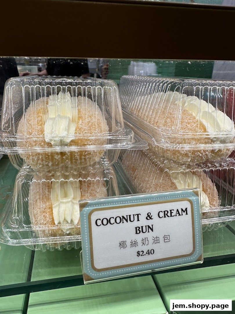 Close-up of coconut and cream buns in clear plastic packaging on a shelf.