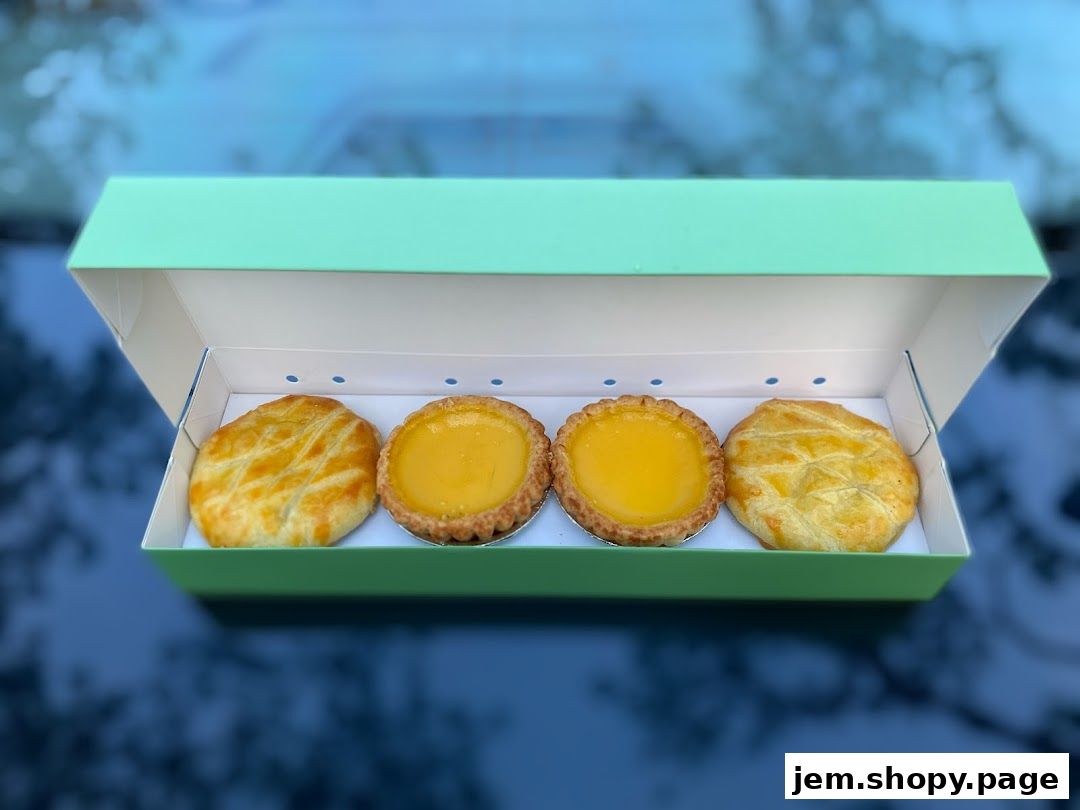 A box of four pastries, including two egg tarts and two savory pies.
