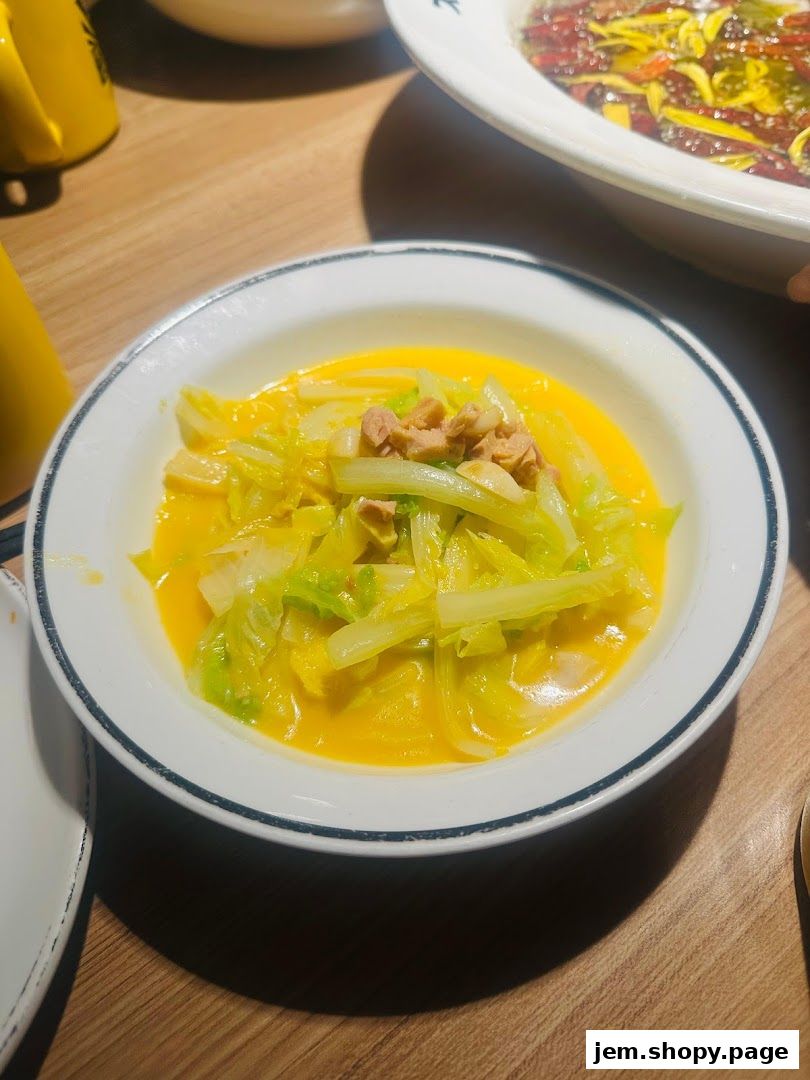 A close-up of a dish featuring cabbage in a creamy yellow sauce, topped with small pieces of meat.