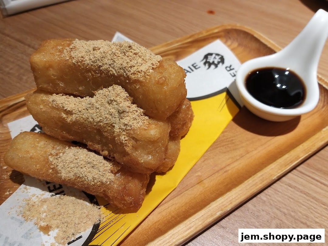 Golden fried dough sticks dusted with powder, served with soy sauce on a wooden tray.