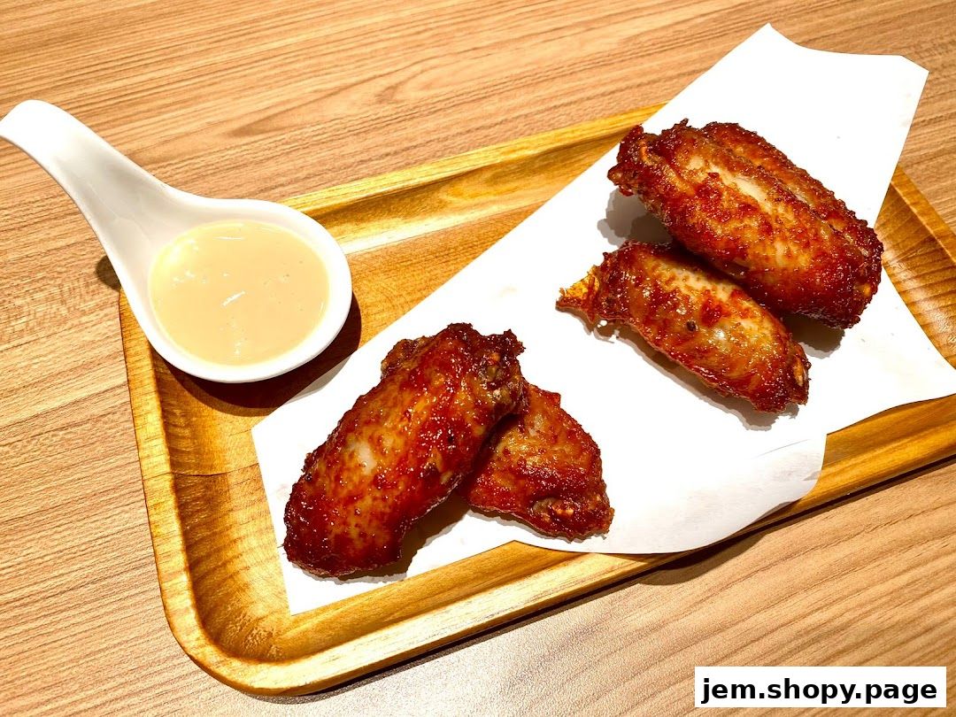 Crispy, glazed chicken wings served with a creamy dipping sauce on a wooden tray.