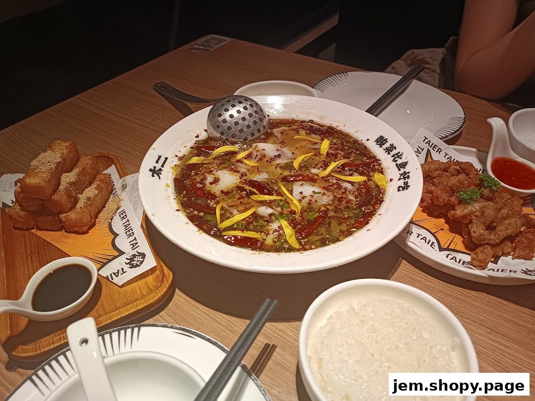 A table laden with delicious dishes from Tai Er Jem, including fish in chili oil, fried snacks, and rice.