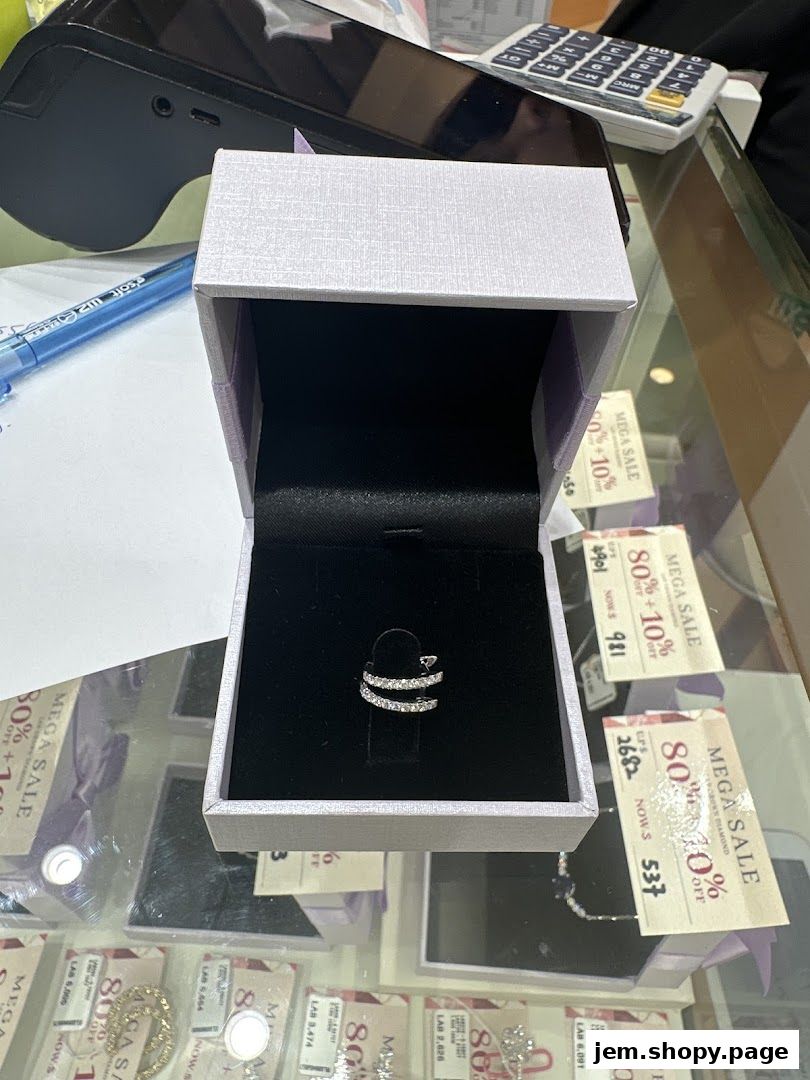 A diamond ring displayed in an open jewelry box with sale tags in the background.