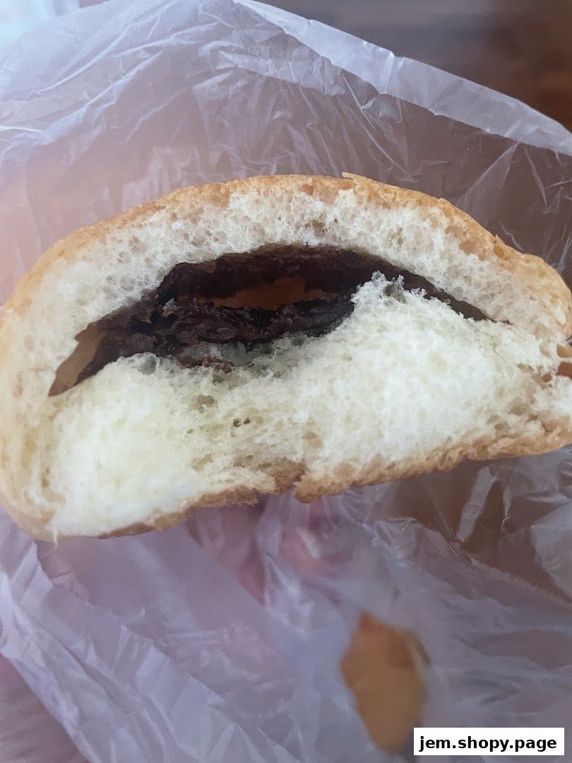 A close-up shot of a delicious chocolate-filled bread bun, partially unwrapped.
