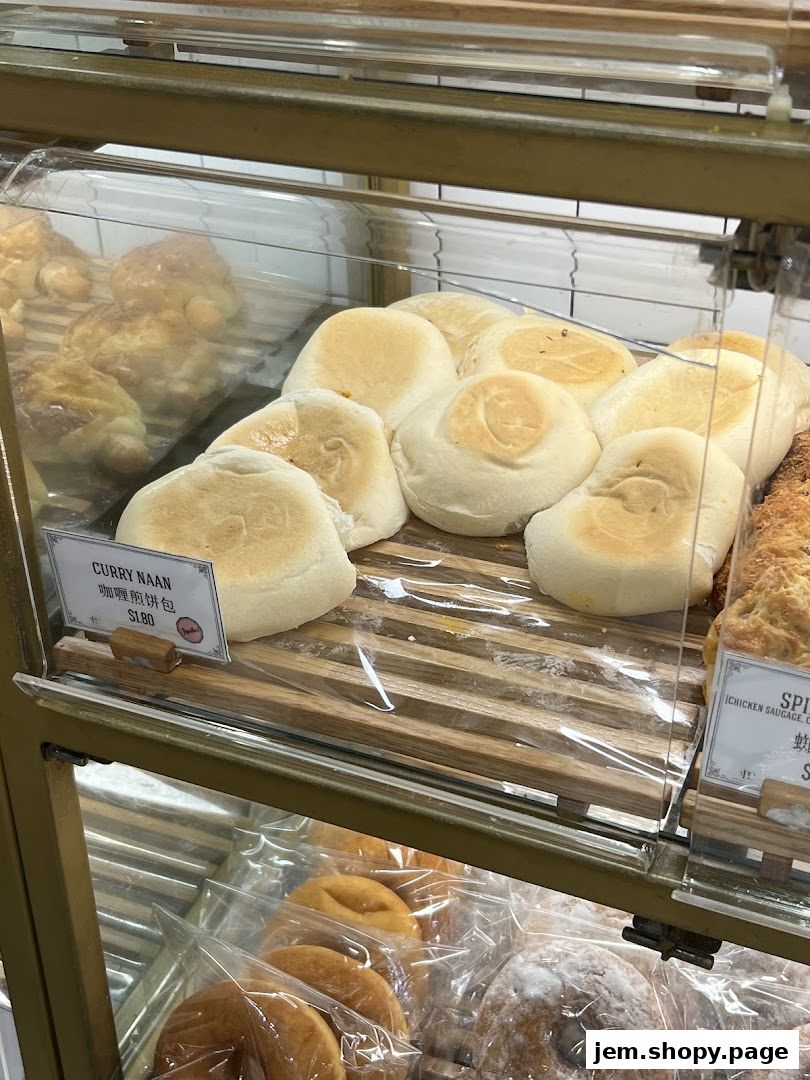 A display case filled with freshly baked bread and pastries, including Curry Naan.