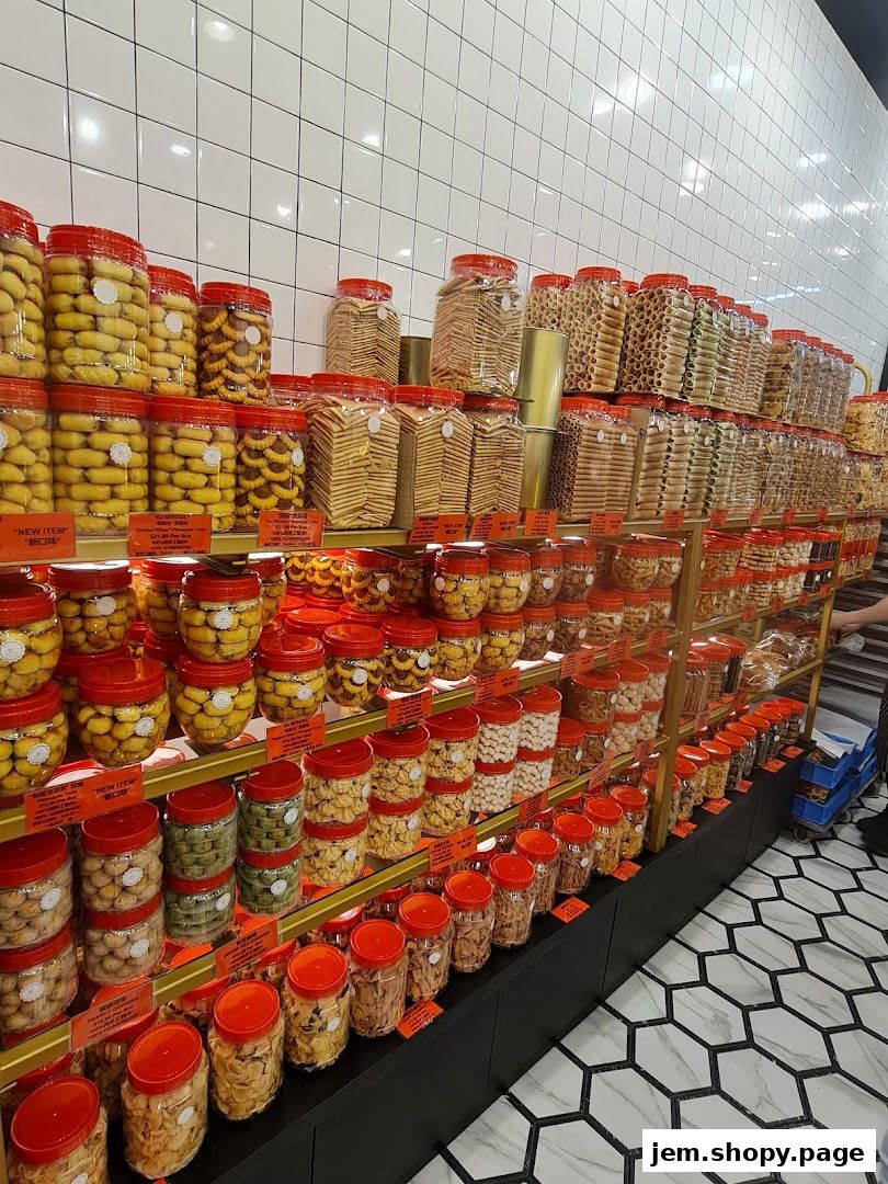 A wide selection of cookies and snacks in clear jars with red lids on display shelves.
