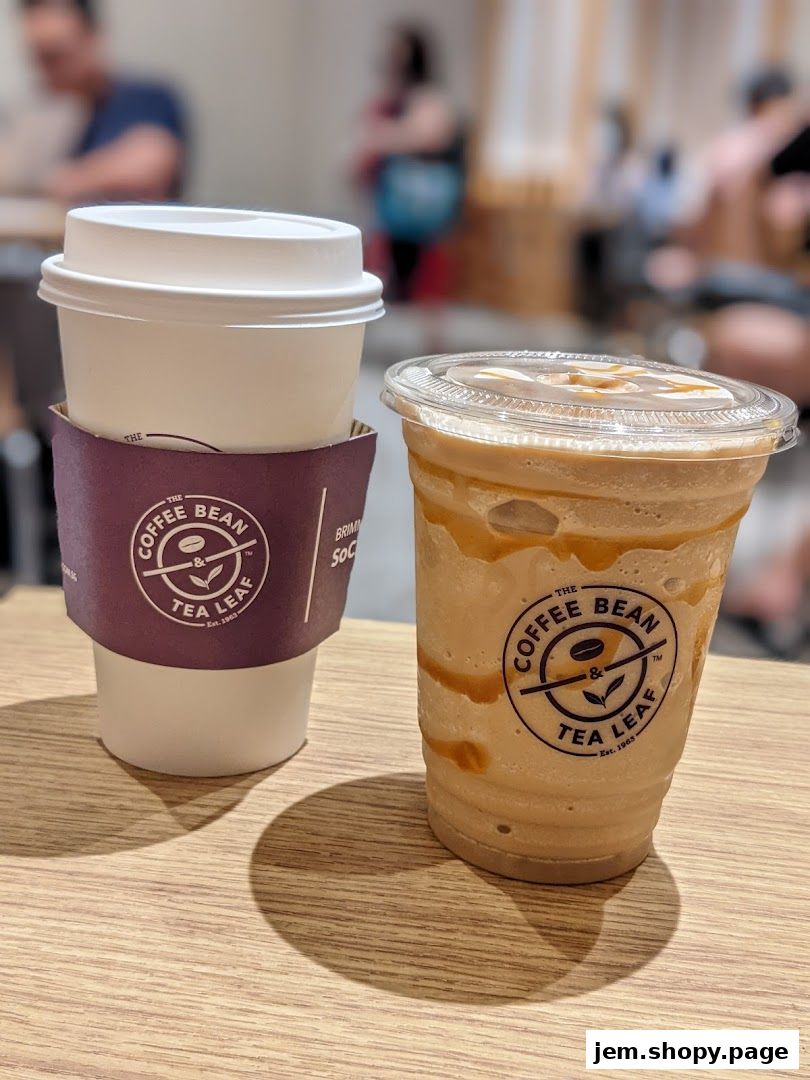 Two beverages from The Coffee Bean & Tea Leaf, one hot and one iced, sit on a wooden table.