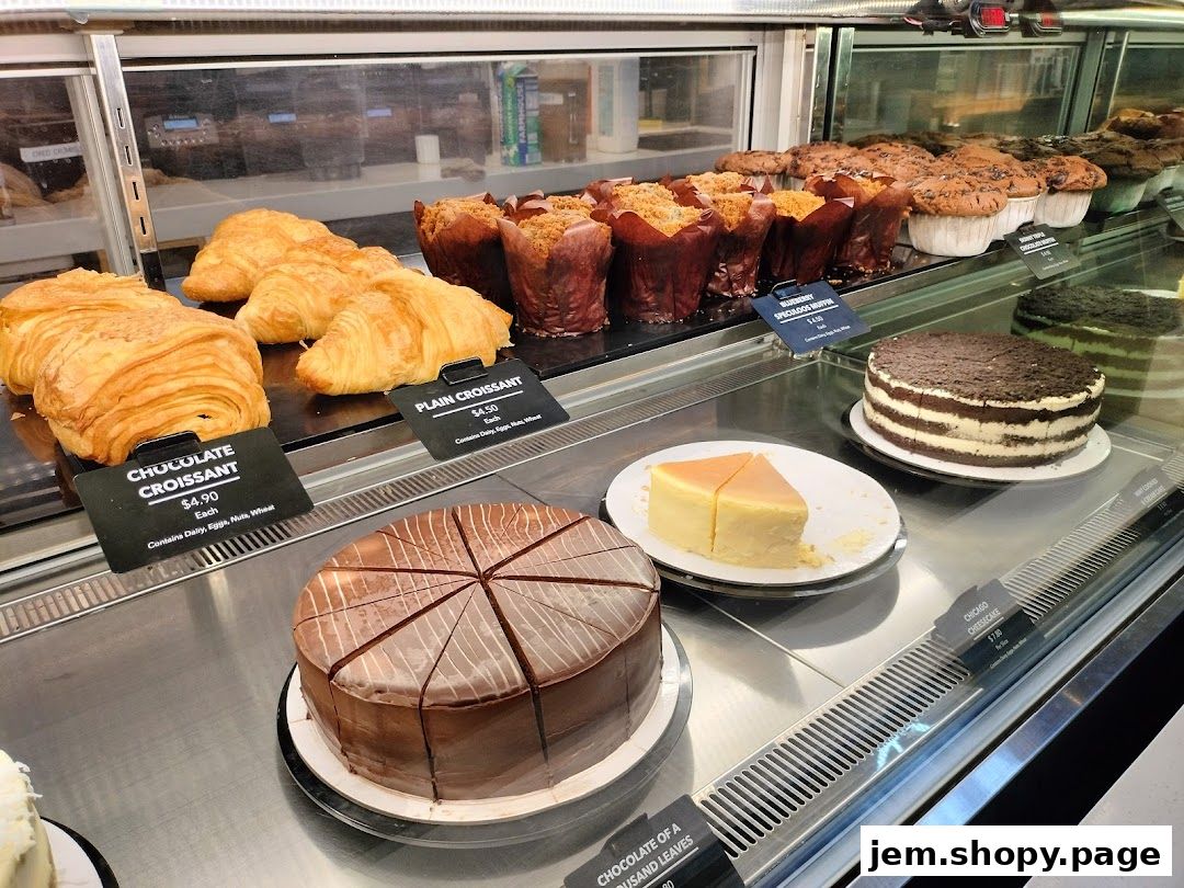 A display case filled with various pastries, including croissants, muffins, and cakes.
