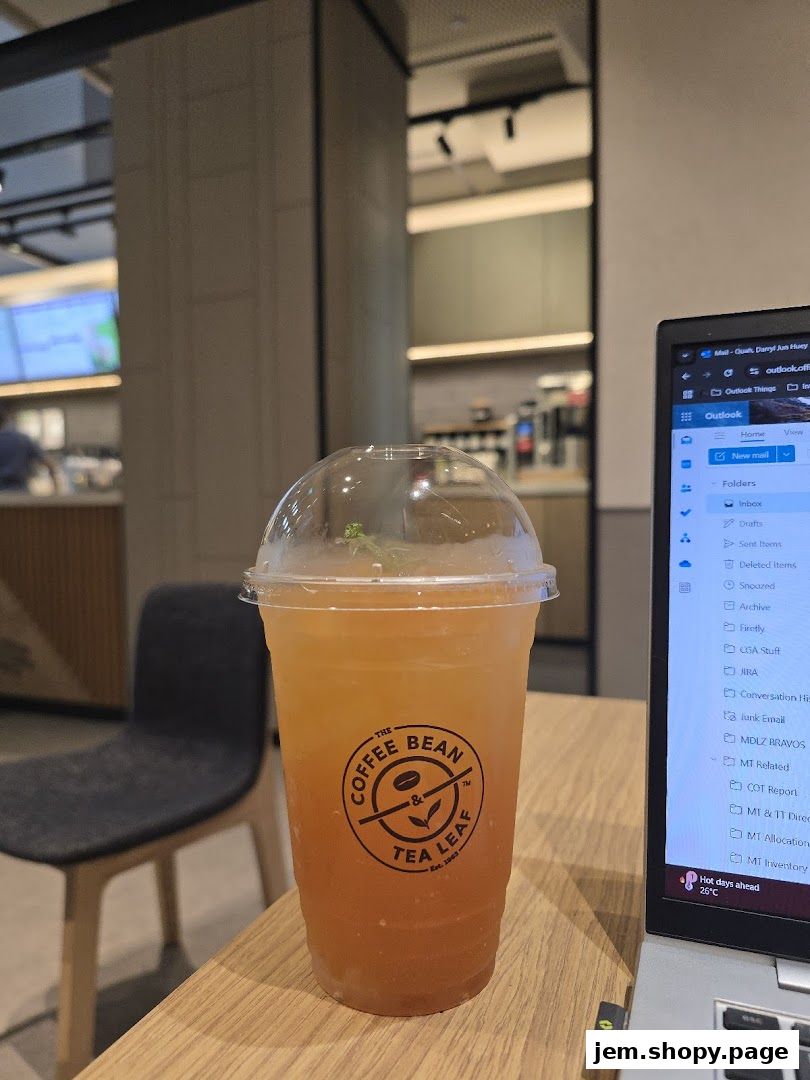 A refreshing iced tea from The Coffee Bean & Tea Leaf sits on a wooden table next to a laptop.