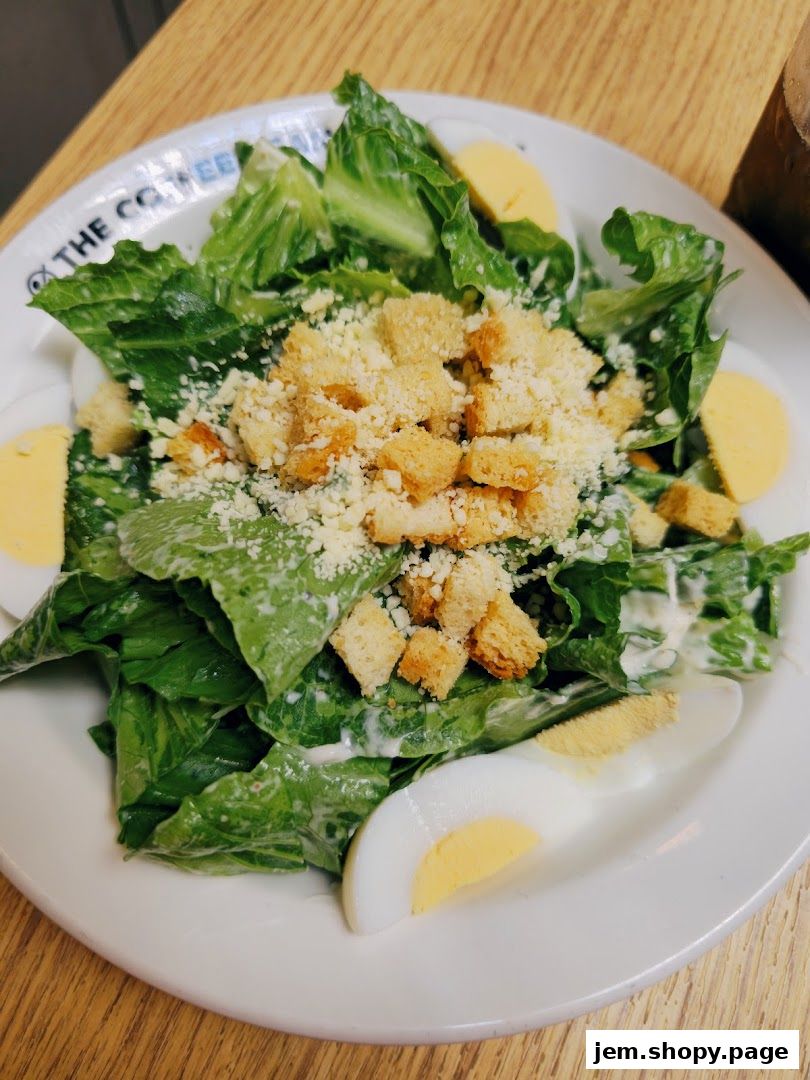 A fresh Caesar salad with croutons and hard-boiled eggs on a white plate.
