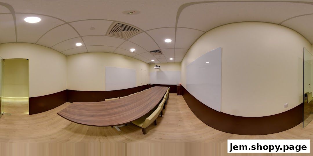 A panoramic view of a modern, well-lit meeting room with a large oval table and whiteboards.