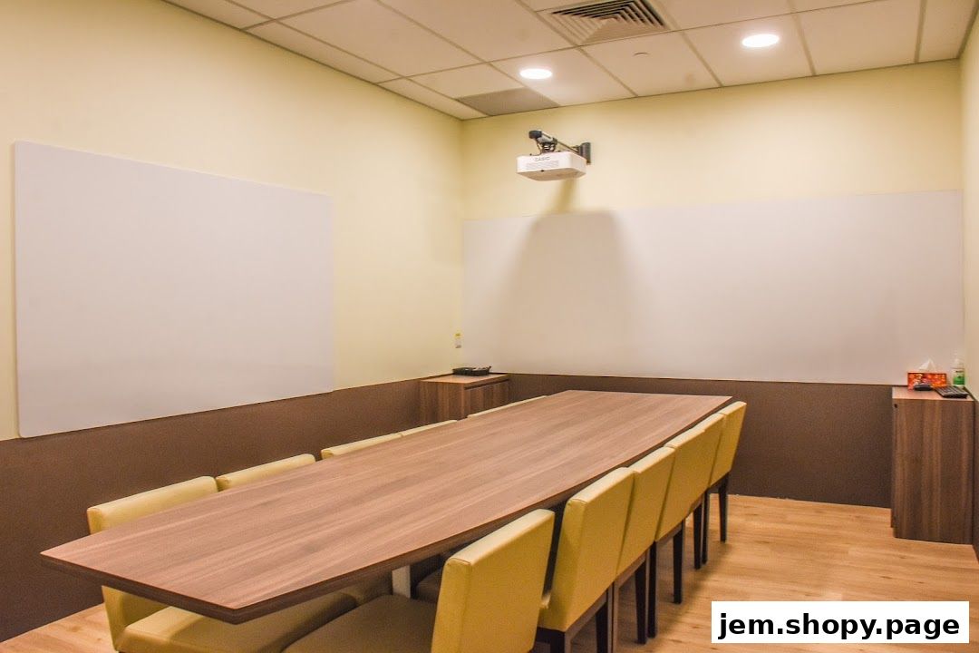 A classroom or meeting room with a long table, chairs, and whiteboards.