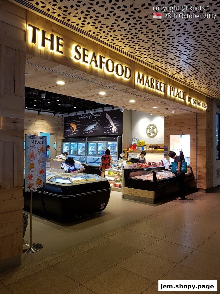 The entrance of 'The Seafood Market Place By Song Fish' with illuminated signage and displays.