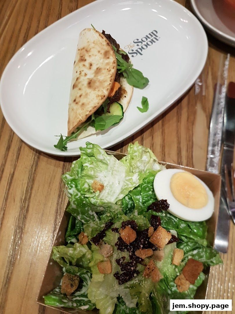 A delicious wrap and a fresh Caesar salad served on a wooden table.