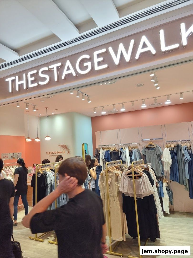 The Stage Walk clothing store interior with racks of apparel and a prominent neon sign.