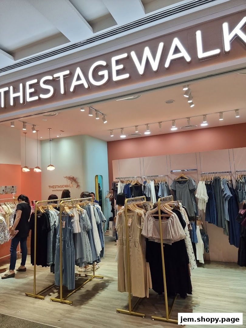 Interior view of 'The Stage Walk' clothing store with racks of apparel and a neon sign.