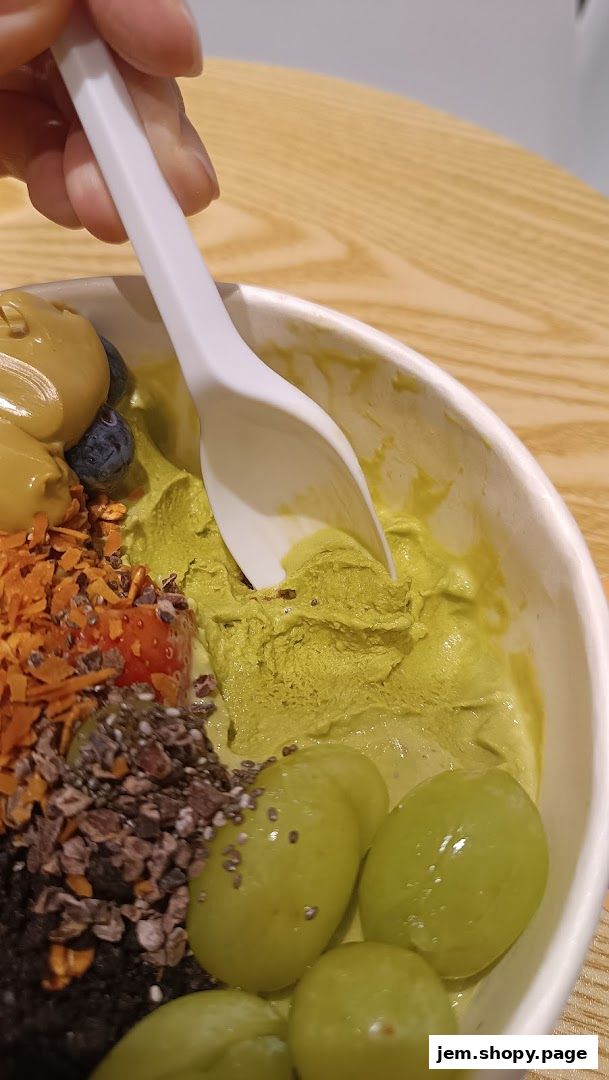 A close-up of a delicious açaí bowl with various toppings being scooped with a spoon.
