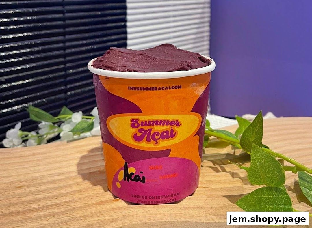 A cup of purple açaí smoothie with the Summer Açaí logo on a wooden surface.