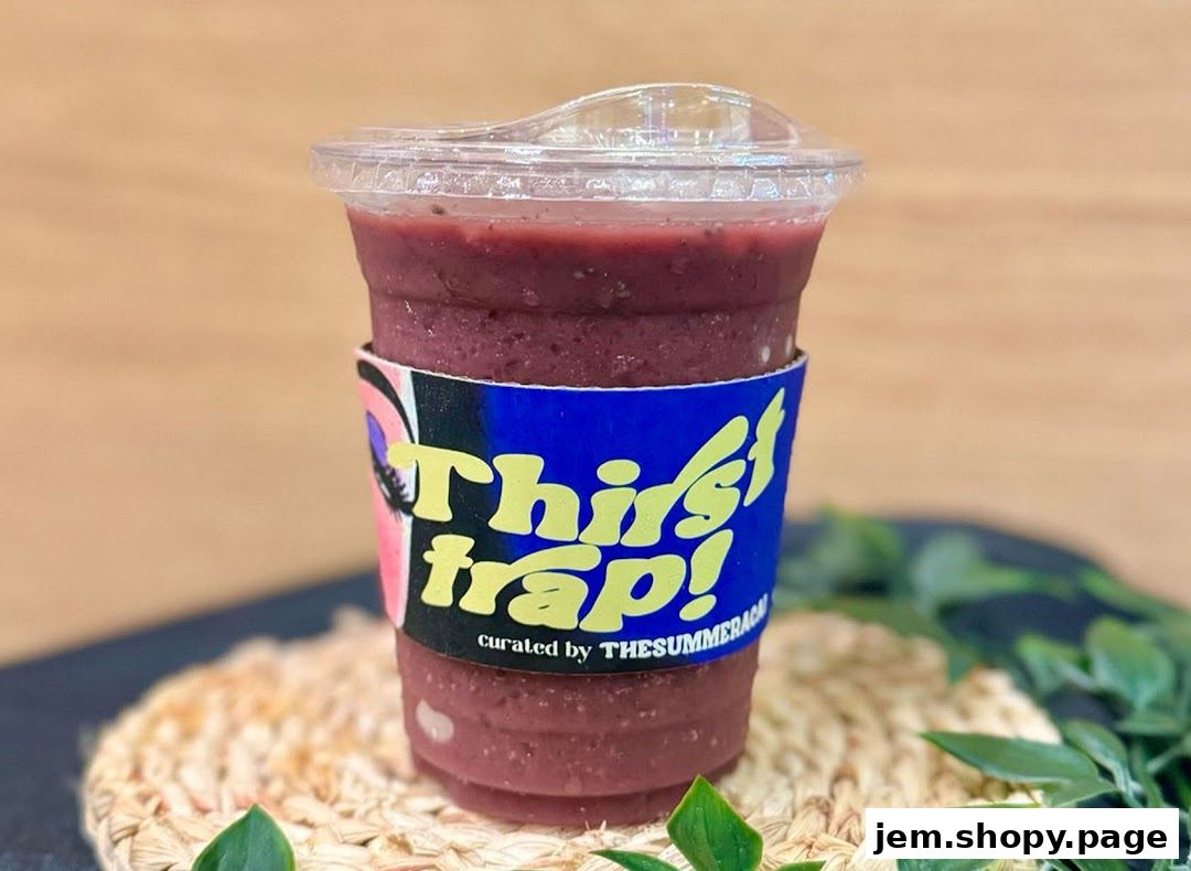 A refreshing berry smoothie in a clear cup with a colorful sleeve.